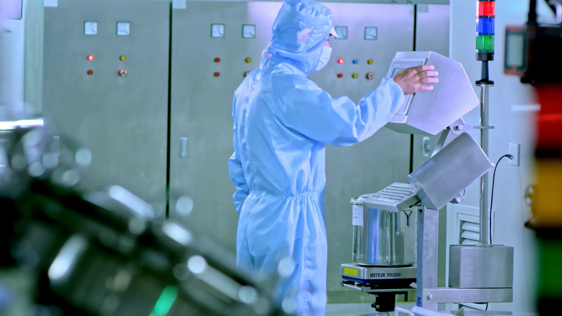 Cleanroom operator weighing and preparing ingredients for cosmetic manufacturing